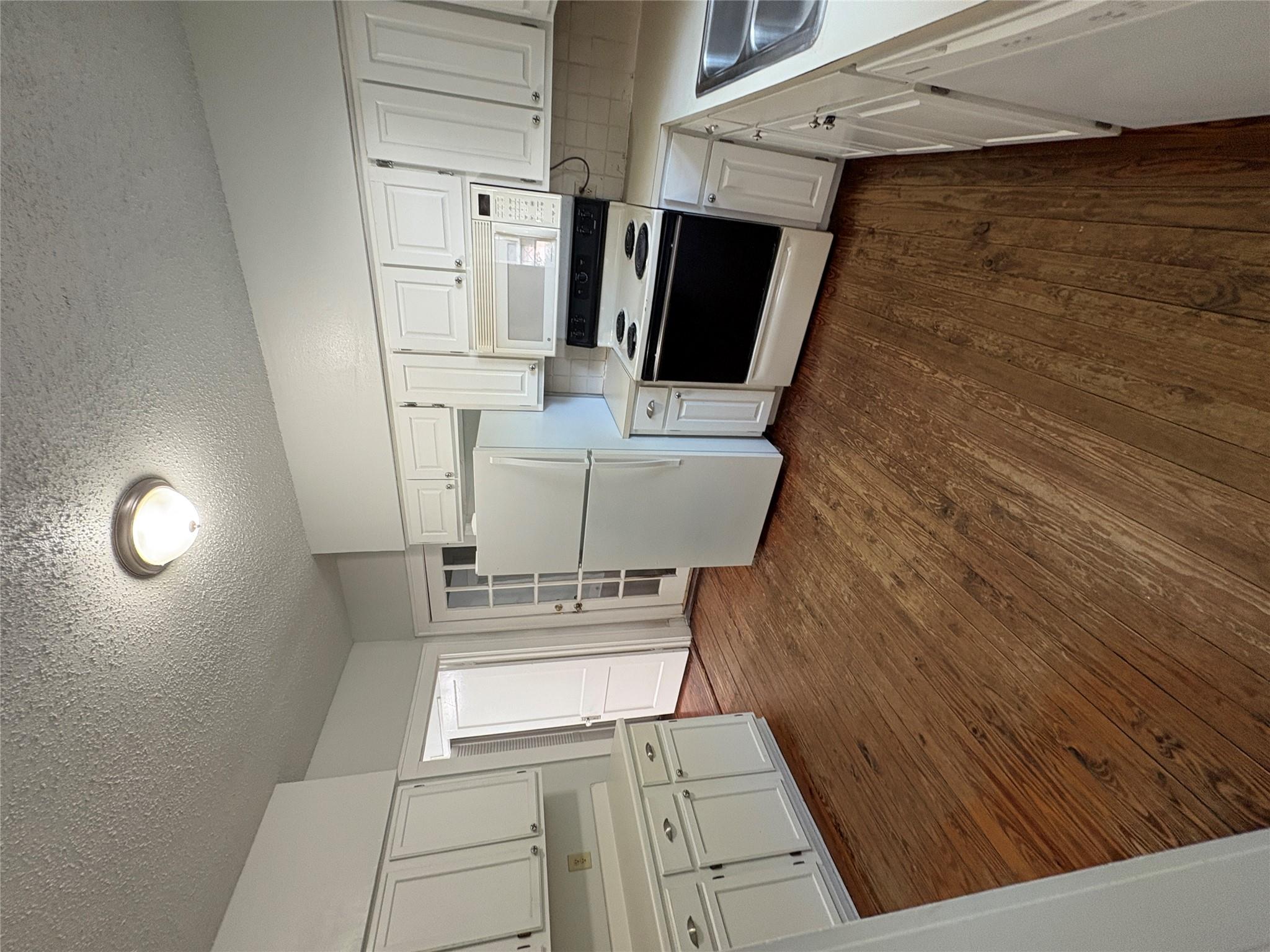 915 West 29th Street Austin, TX 78705 - Photo 12 of 20 Kitchen featuring wood-finish flooring, white cabinetry, light-toned countertops, and a white appliance suite including a refrigerator, range, and built-in microwave