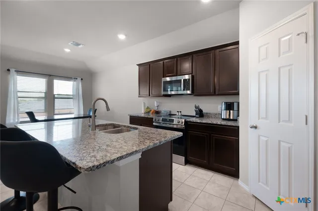 a kitchen with stainless steel appliances granite countertop a sink stove and refrigerator
