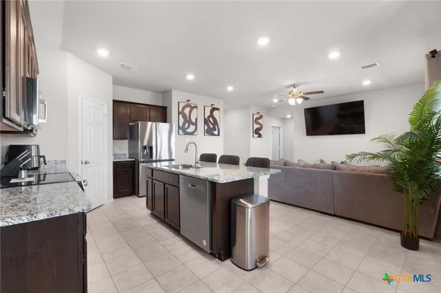 a kitchen with stainless steel appliances kitchen island granite countertop a sink and a stove top oven with wooden floor