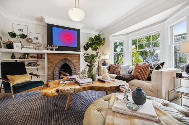 a living room with furniture a fireplace and large windows