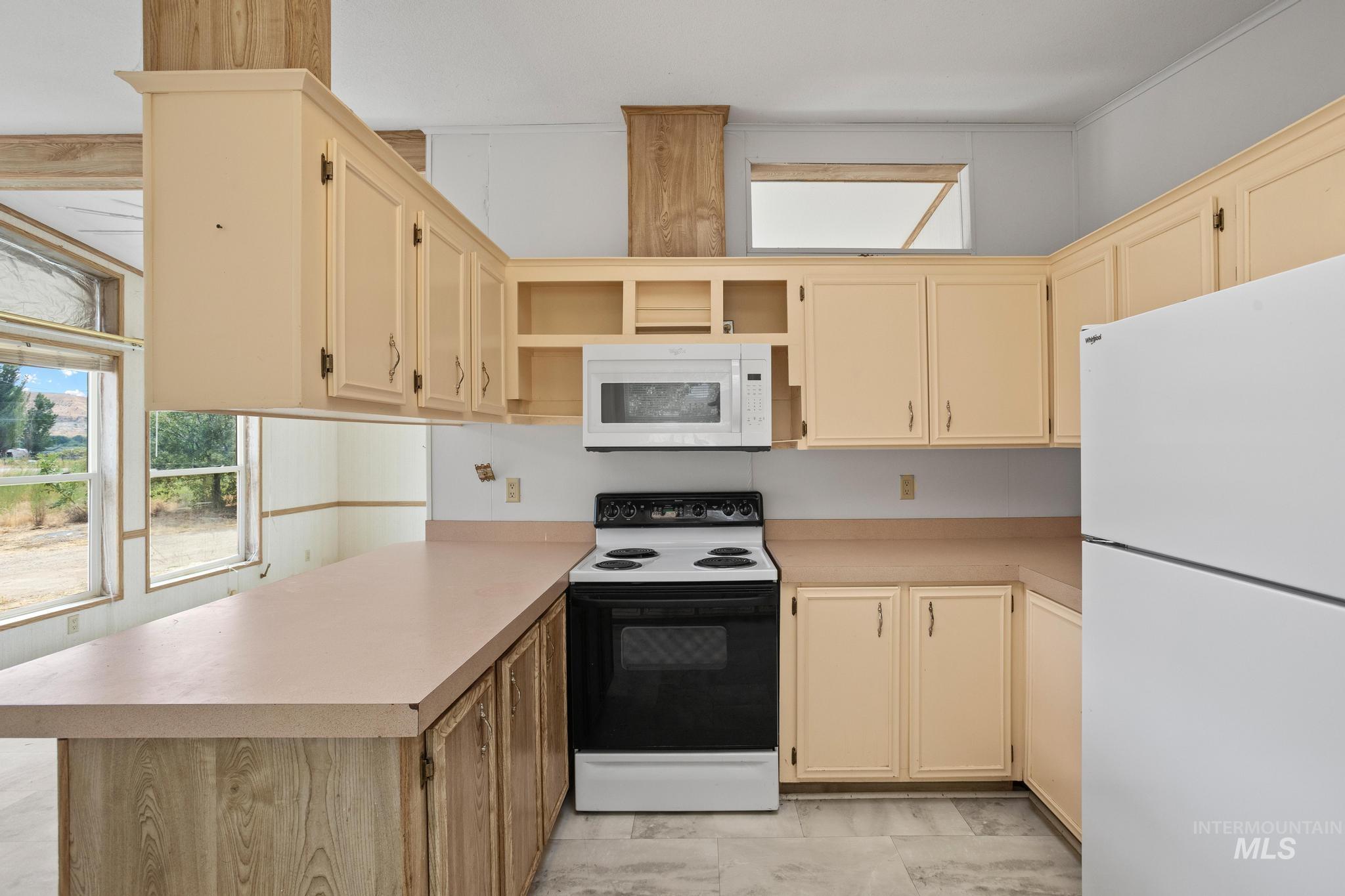 3680 South Mill Road Emmett, ID 83617 - Photo 19 of 38 Kitchen featuring extensive counter space, ample cabinetry, a white microwave, a black and white electric range, and a white refrigerator