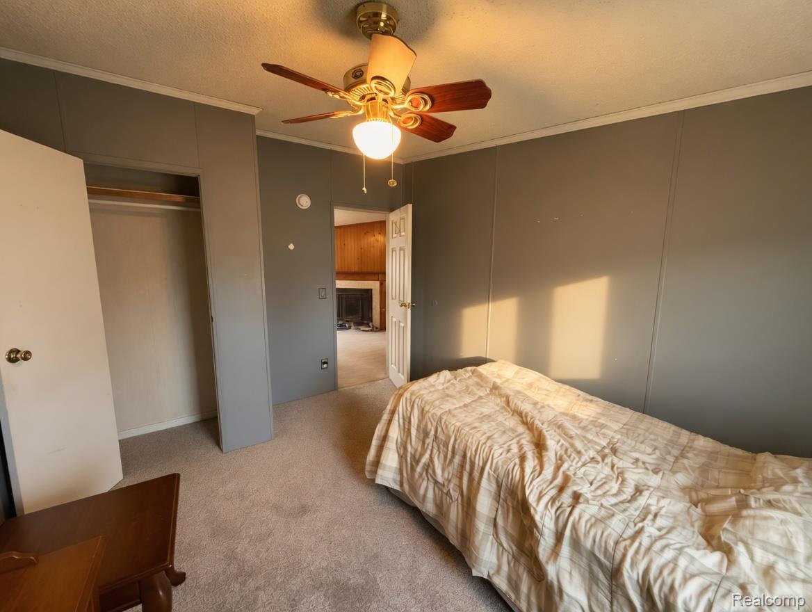 6988 McKean Road Ypsilanti, MI 48197 - Photo 10 of 21 Bedroom with carpet, ornamental molding, ceiling fan, a closet, and a textured ceiling