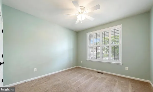 an empty room with wooden floor ceiling fan and windows