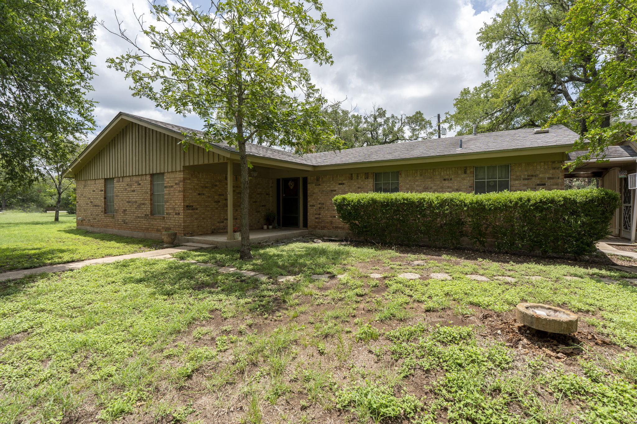 Front of house with brick siding, a lawn, and a patio