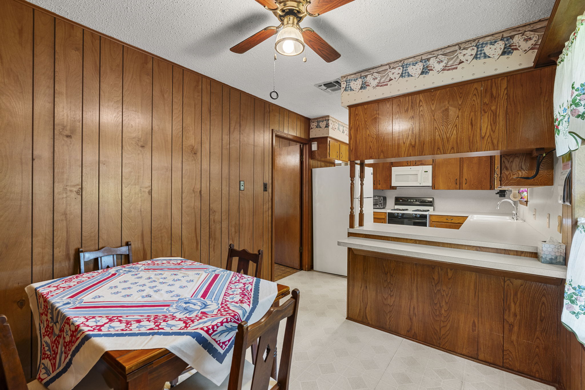 3511 Wyldwood Road Austin, TX 78739 - Photo 16 of 40 Dining space featuring light floors, a ceiling fan, wood walls, and a textured ceiling