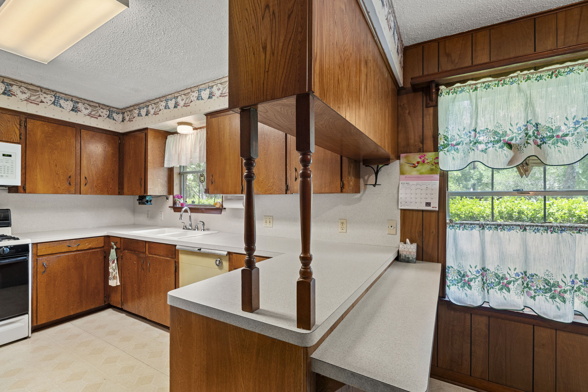 3511 Wyldwood Road Austin, TX 78739 - Photo 17 of 40 Kitchen featuring a textured ceiling, white appliances, light countertops, brown cabinets, and a peninsula