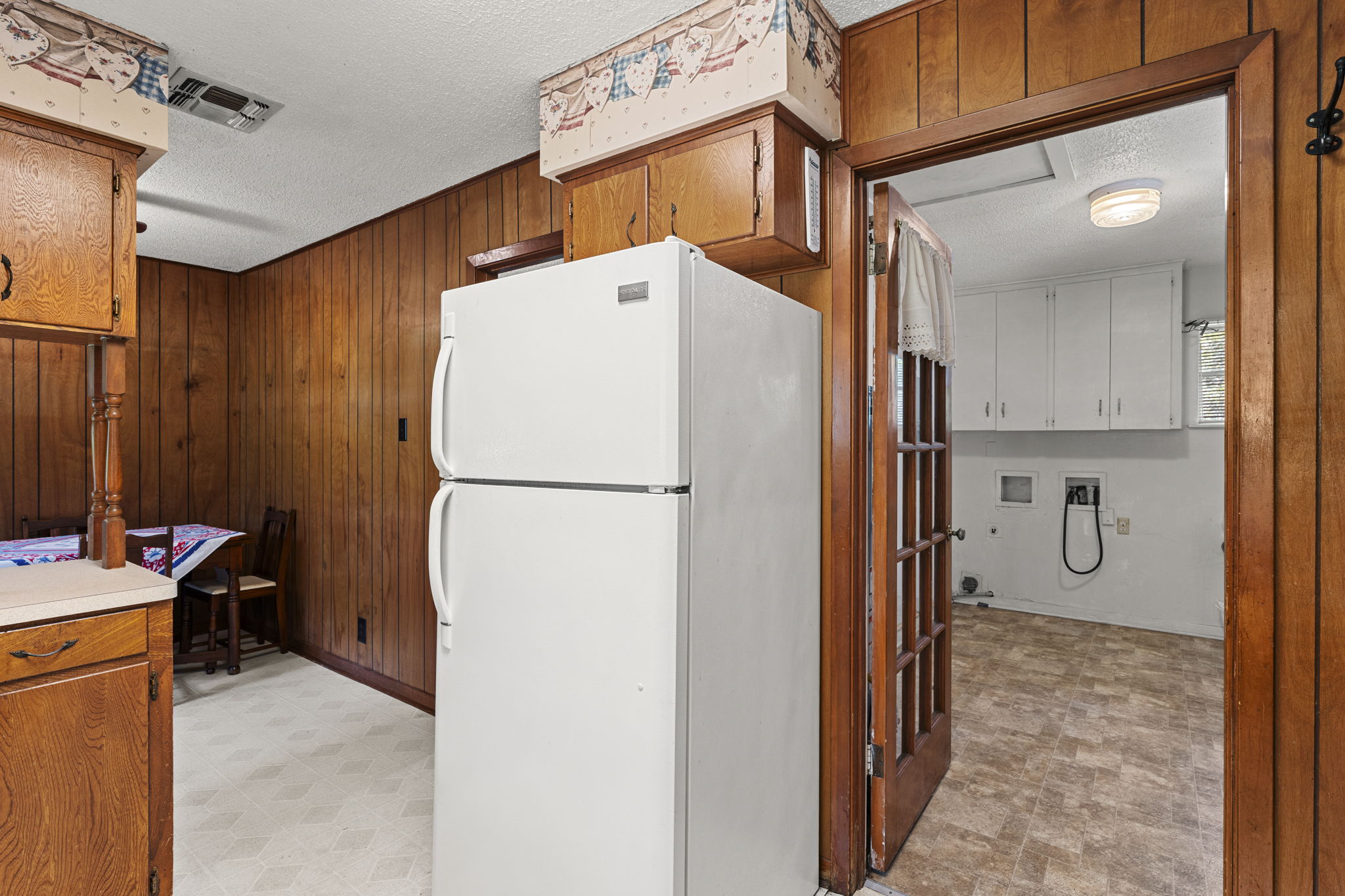 3511 Wyldwood Road Austin, TX 78739 - Photo 18 of 40 Kitchen with freestanding refrigerator, a textured ceiling, wood walls, light floors, and light countertops