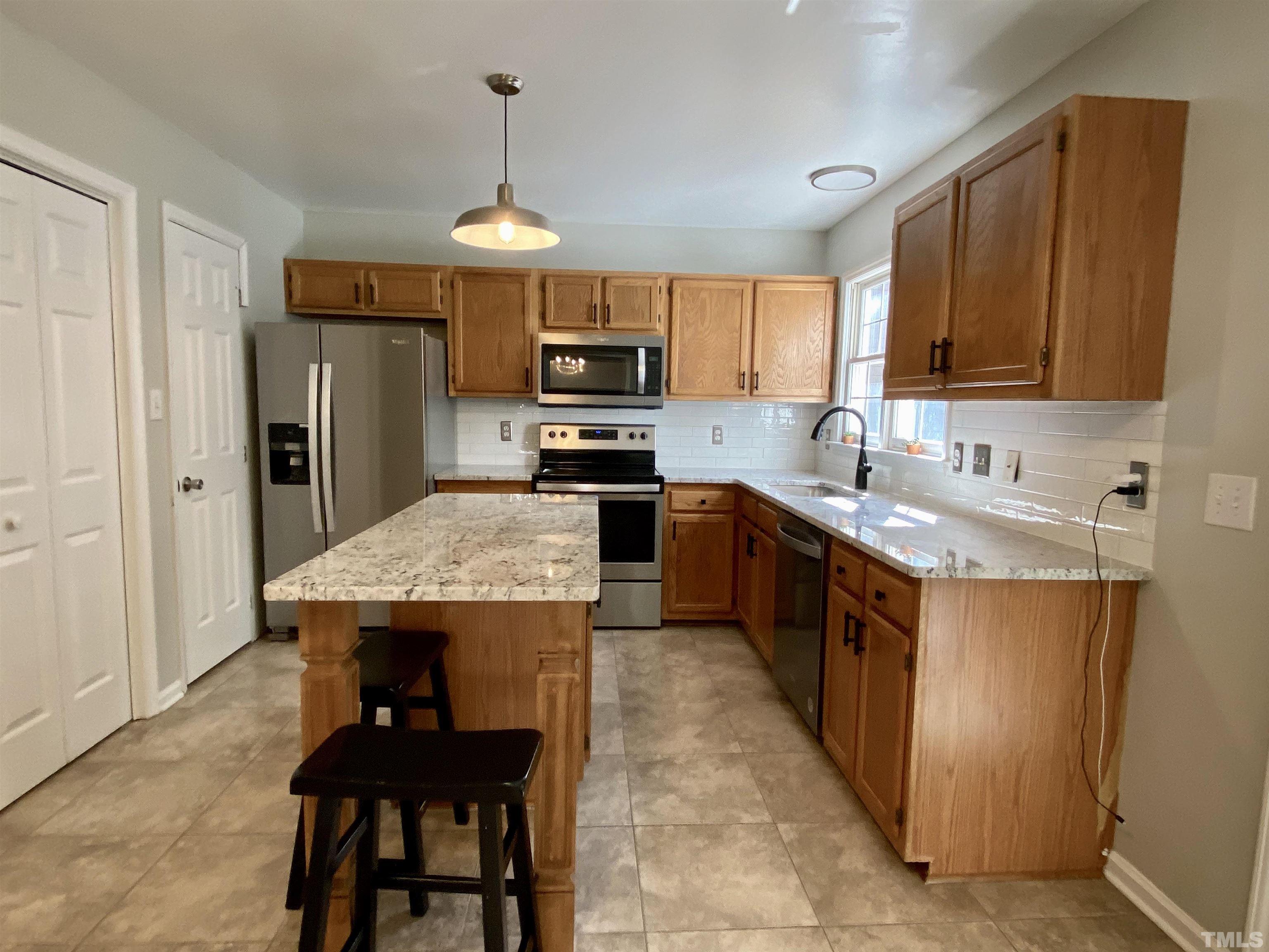 302 Bebington Drive Cary, NC 27513 - Photo 12 of 27 a kitchen with kitchen island granite countertop a sink a counter top space and stainless steel appliances