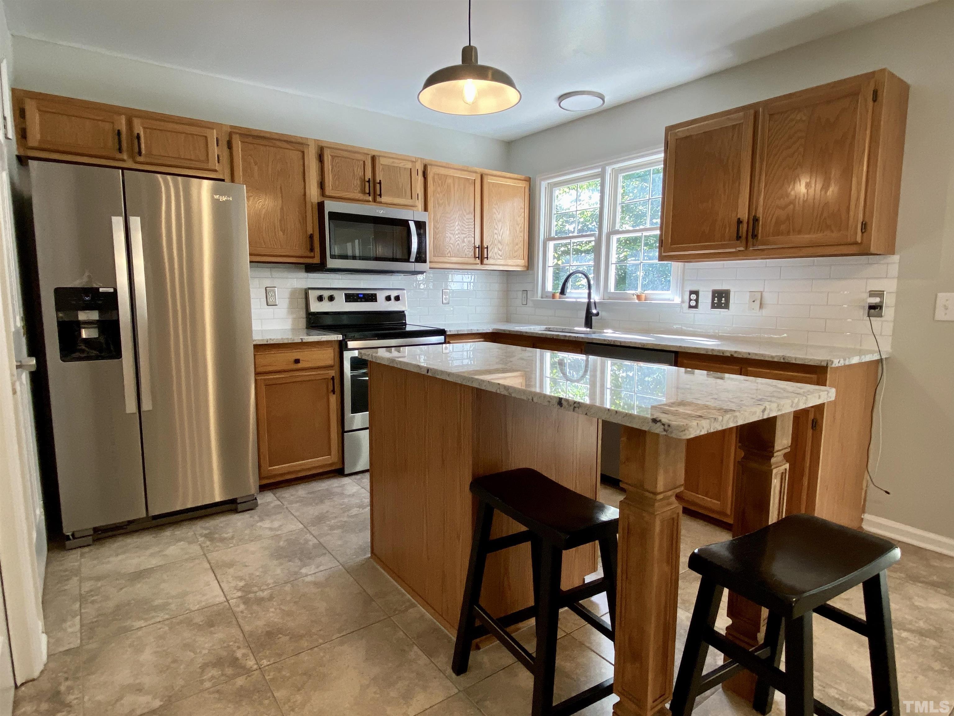 302 Bebington Drive Cary, NC 27513 - Photo 15 of 27 a kitchen with stainless steel appliances a table chairs refrigerator and microwave