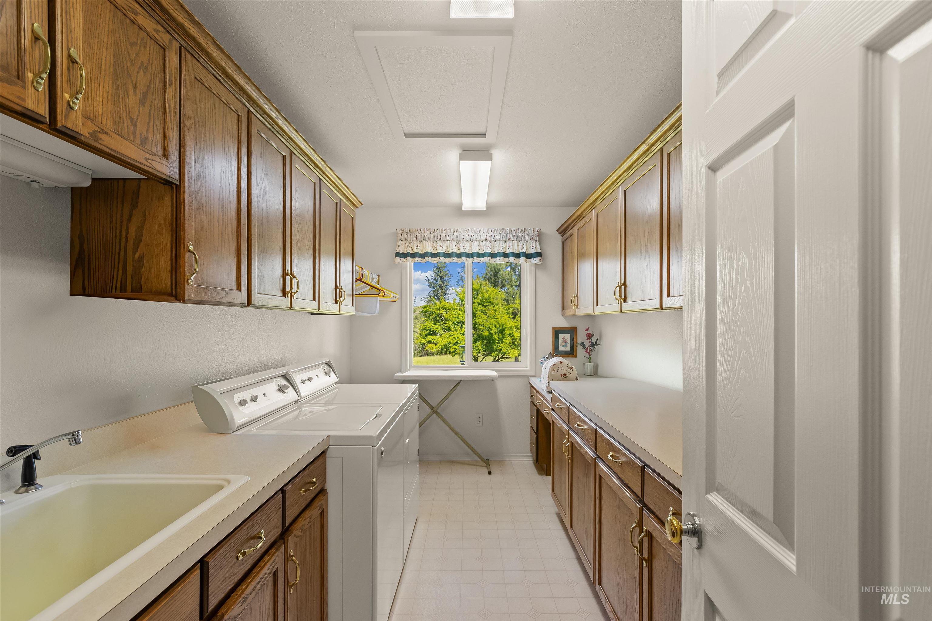 743 Wall Crk Road Stites, ID 83552 - Photo 30 of 48 Functional laundry area featuring extensive wood-finish cabinetry, ample countertop space, a utility sink, and a window providing natural light