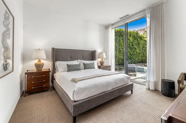 a bedroom with a bed a large window and wooden floor