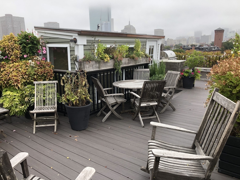 69 Rutland Street, Unit 3 Boston, MA 02118 - Photo 36 of 39 a view of a patio with table and chairs potted plants with wooden floor and fence