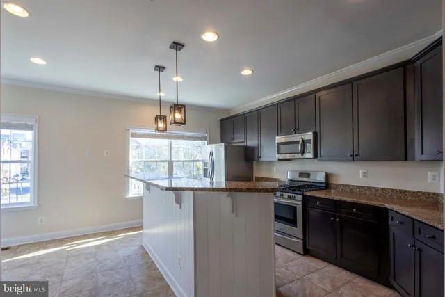 a kitchen with stainless steel appliances granite countertop a sink a stove a refrigerator cabinets and a window