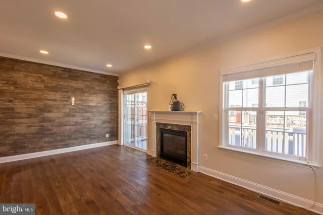 a view of an empty room with wooden floor fireplace and a window