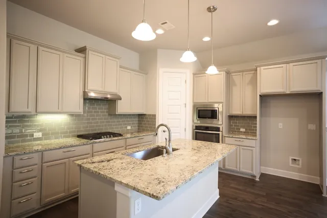 a kitchen with granite countertop a sink refrigerator and cabinets