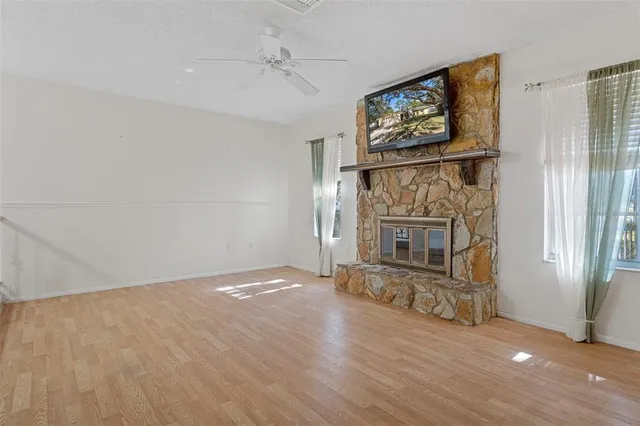 an empty room with wooden floor fireplace and windows