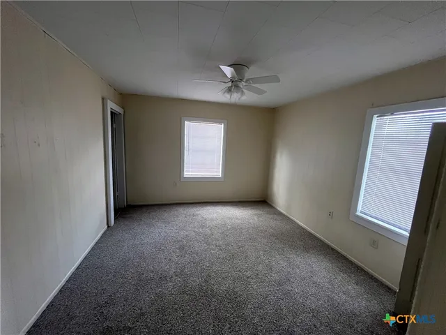 an empty room with windows and fan