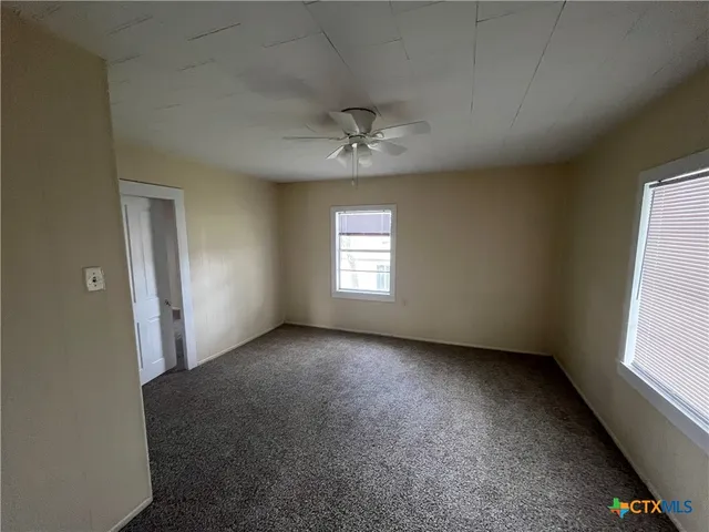 an empty room with a window and a ceiling fan