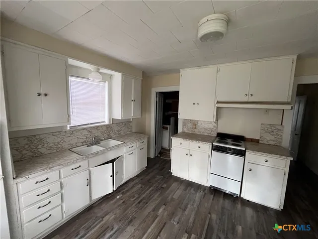 a kitchen with granite countertop a sink stove and cabinets
