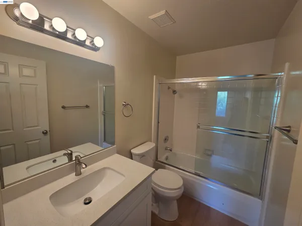a bathroom with a granite countertop bathtub shower and toilet