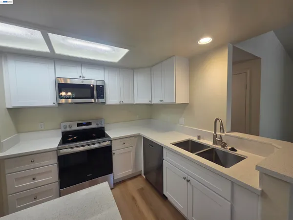 a kitchen with stainless steel appliances white cabinets and a stove top oven