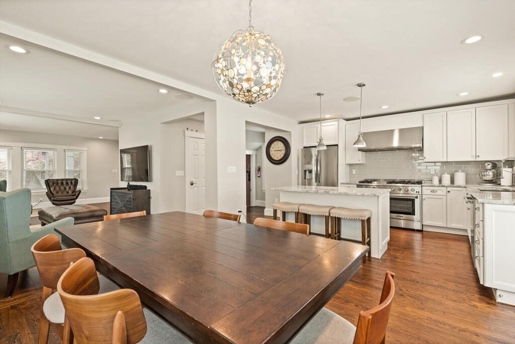 43 Guild Street Medford, MA 02155 - Photo 7 of 33 a kitchen with stainless steel appliances granite countertop a stove top oven a sink a dining table and chairs with wooden floor
