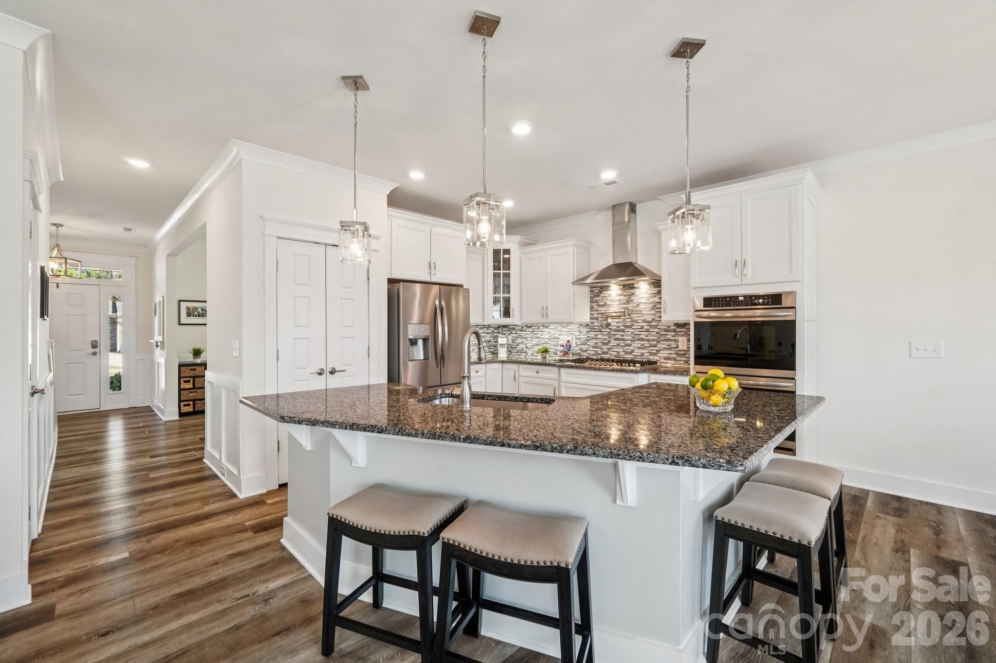 4093 Clapton Drive Lancaster, SC 29720 - Photo 13 of 48 a kitchen with kitchen island a dining table chairs wooden floor and a chandelier