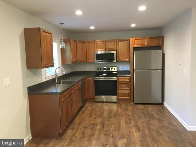 a kitchen with stainless steel appliances granite countertop a refrigerator a stove top oven a sink and dishwasher