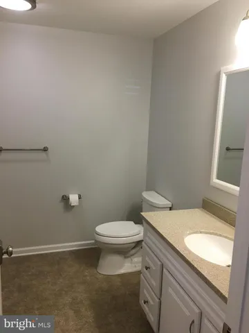 a bathroom with a granite countertop toilet and a sink