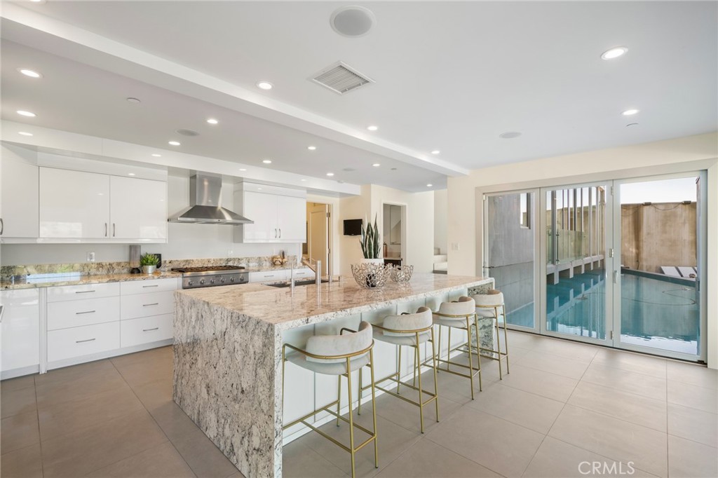 9716 Oak Pass Road Beverly Hills, CA 90210 - Photo 14 of 63 a large kitchen with kitchen island granite countertop lots of white cabinets a dining table and chairs