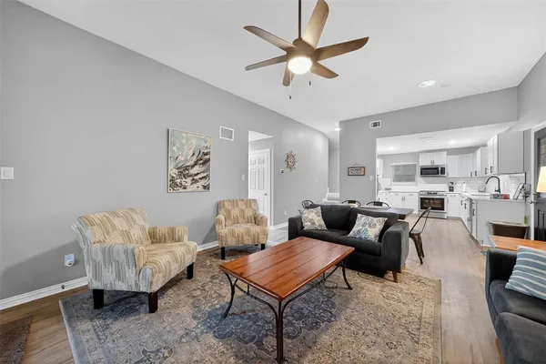 a living room with furniture kitchen view and a chandelier