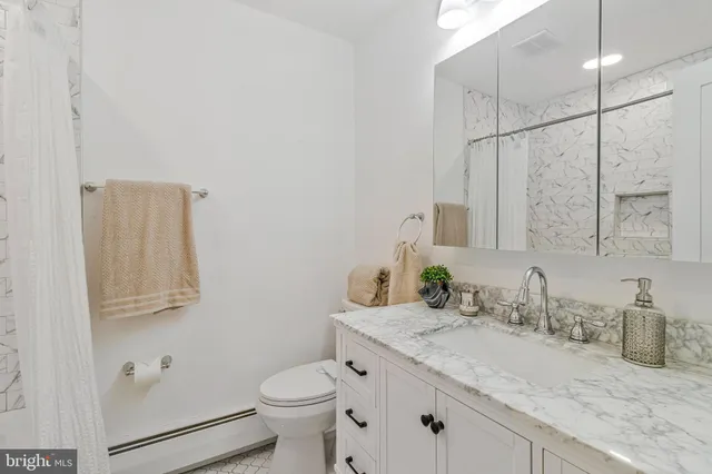 a bathroom with a granite countertop sink a toilet and mirror