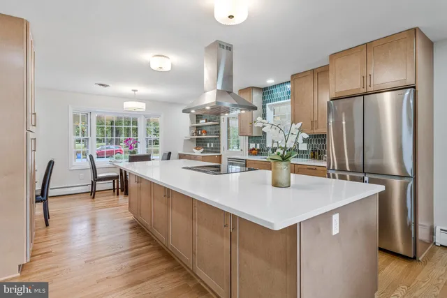 a kitchen with stainless steel appliances granite countertop a table chairs and a refrigerator