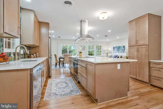 a kitchen with kitchen island granite countertop a sink a counter top space stainless steel appliances and cabinets