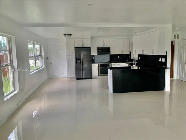 a kitchen with stainless steel appliances a refrigerator a stove a sink a microwave a dining table and chairs