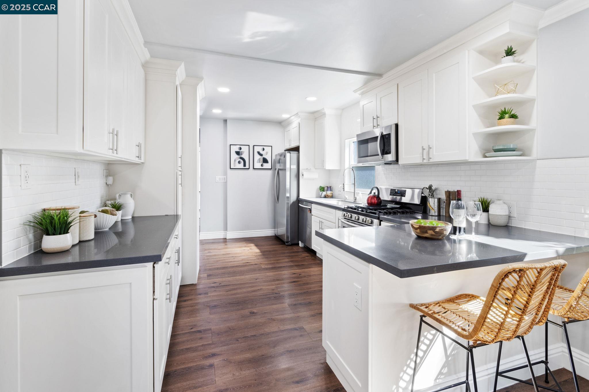 4010 Masterson Street Oakland, CA 94619 - Photo 9 of 27 a kitchen with stainless steel appliances kitchen island granite countertop a sink dishwasher a stove and white cabinets with wooden floor