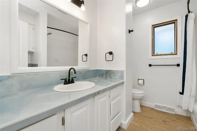 a bathroom with a granite countertop sink toilet and mirror