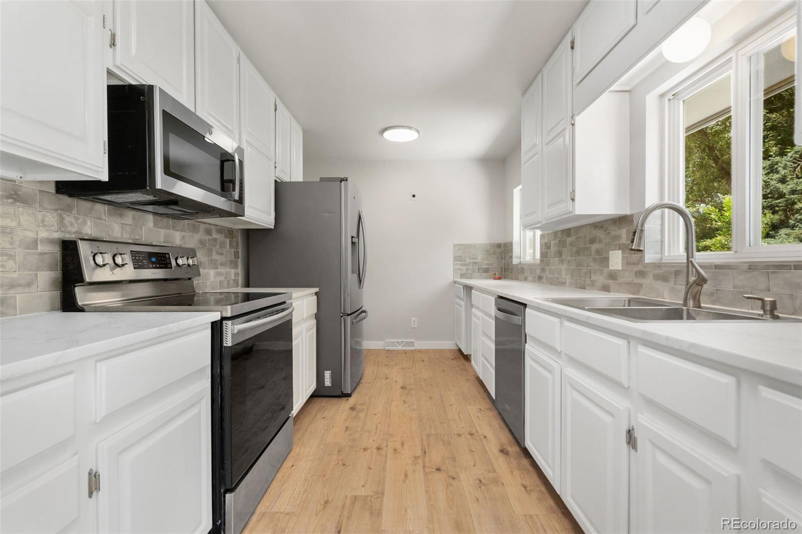 1304 South Lemay Avenue Fort Collins, CO 80524 - Photo 7 of 21 a kitchen with stainless steel appliances granite countertop a sink a stove top oven a refrigerator with grey cabinets and wooden floor