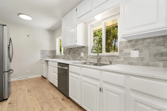 a kitchen with a sink cabinets stainless steel appliances and a window
