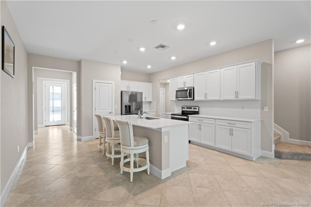 a kitchen with white cabinets and chairs