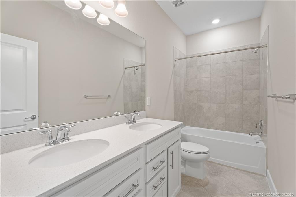 1857 Southeast Tarni Way Stuart, FL 34996 - Photo 16 of 21 a bathroom with a granite countertop sink a toilet a mirror a bathtub and shower