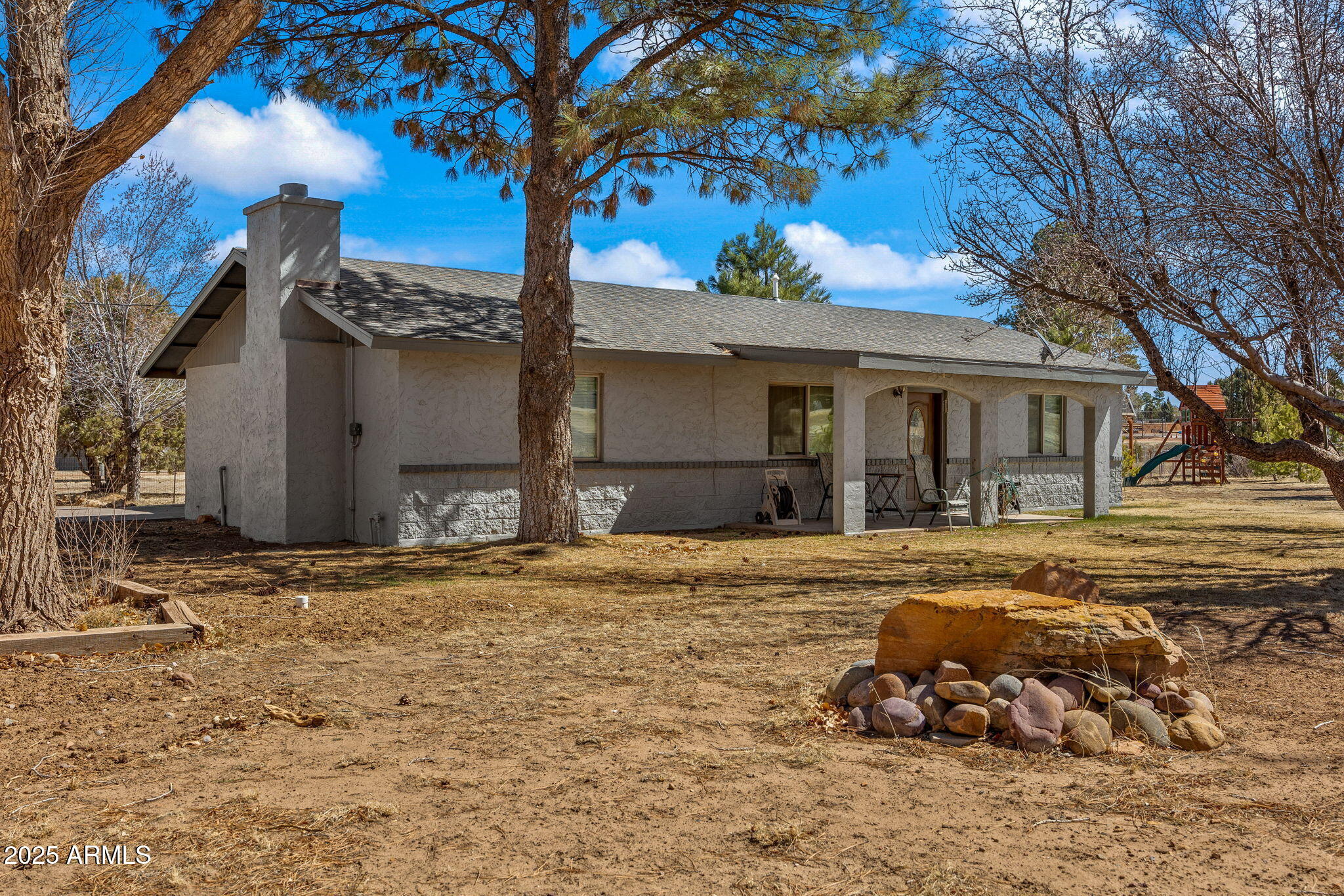 a backyard of a house with table and chairs under an umbrella