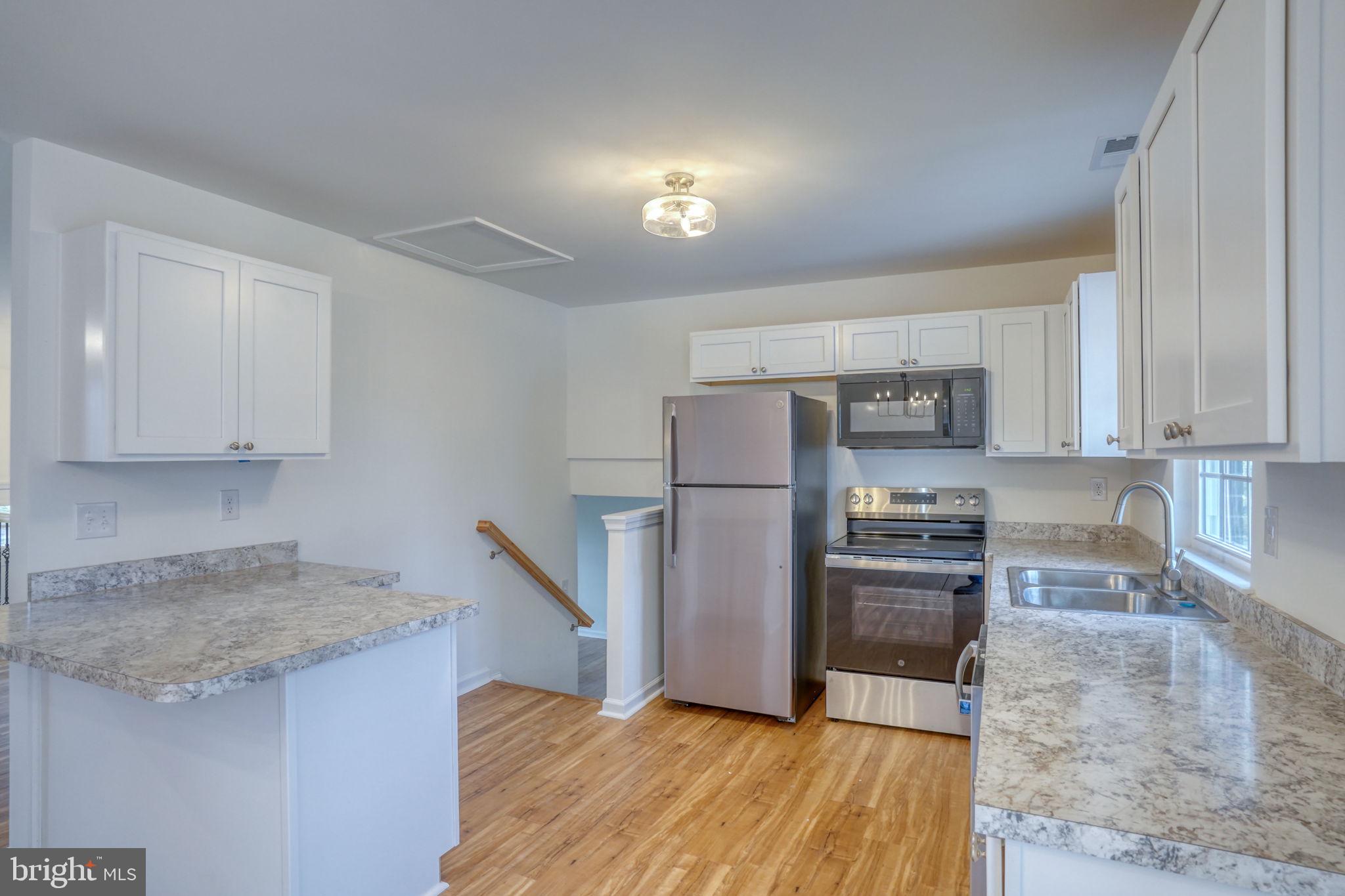 811 Sunset Terrace Dover, DE 19904 - Photo 14 of 45 a kitchen with granite countertop a refrigerator a stove a sink and white cabinets