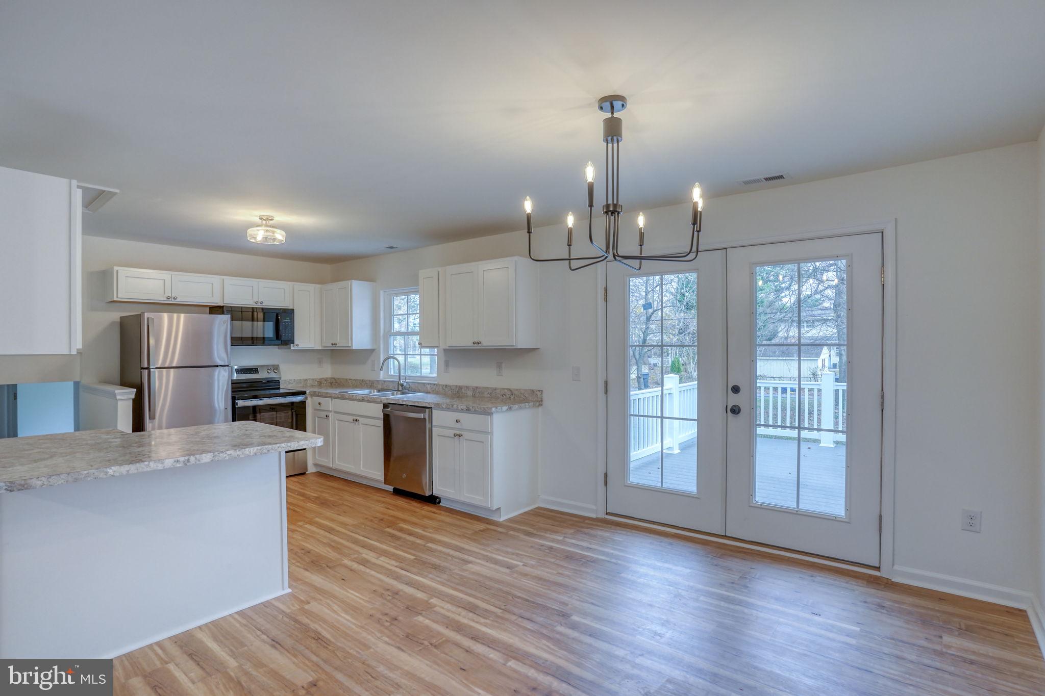 811 Sunset Terrace Dover, DE 19904 - Photo 10 of 45 a kitchen with stainless steel appliances kitchen island granite countertop a refrigerator a sink dishwasher a stove and a dining table with wooden floor