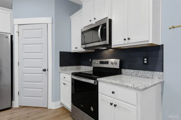 a kitchen with granite countertop white cabinets and stainless steel appliances
