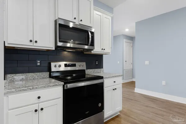 a kitchen with granite countertop white cabinets and black appliances