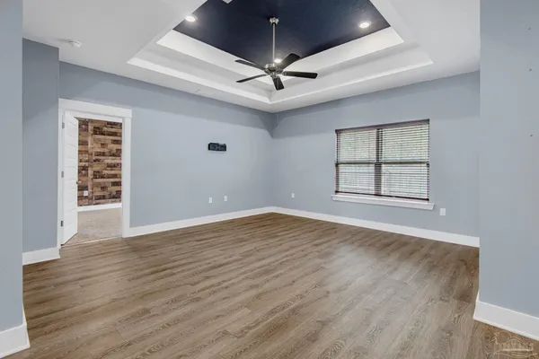 an empty room with wooden floor chandelier ceiling fan and windows