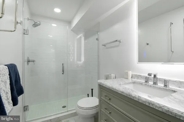 a bathroom with a granite countertop sink a mirror a shower and a toilet