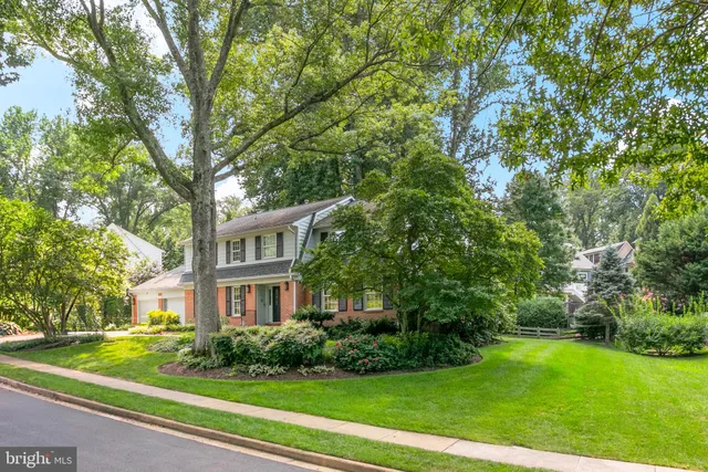 a view of a brick building next to a yard with big trees
