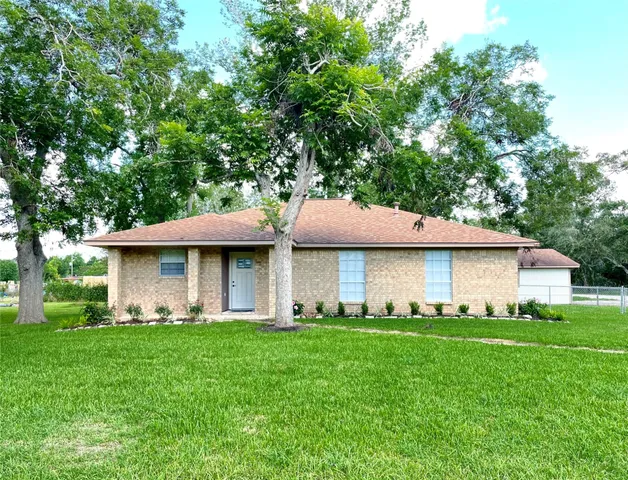 a view of a yard in front of a house with large tree